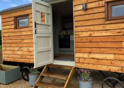 Wood panelled shepherd hut with barn door open. Glamping. cottage core. toghill House Farm. Wick. Bath